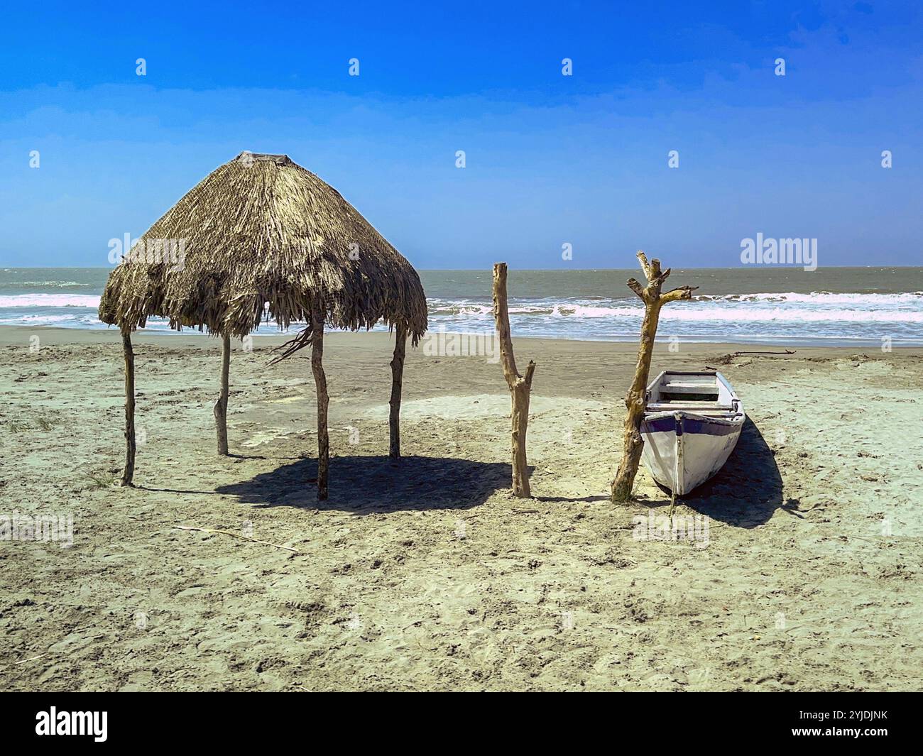 Straw sun shelter and small wooden boat on a beach. No people. - Smartphone Captured Stock Image