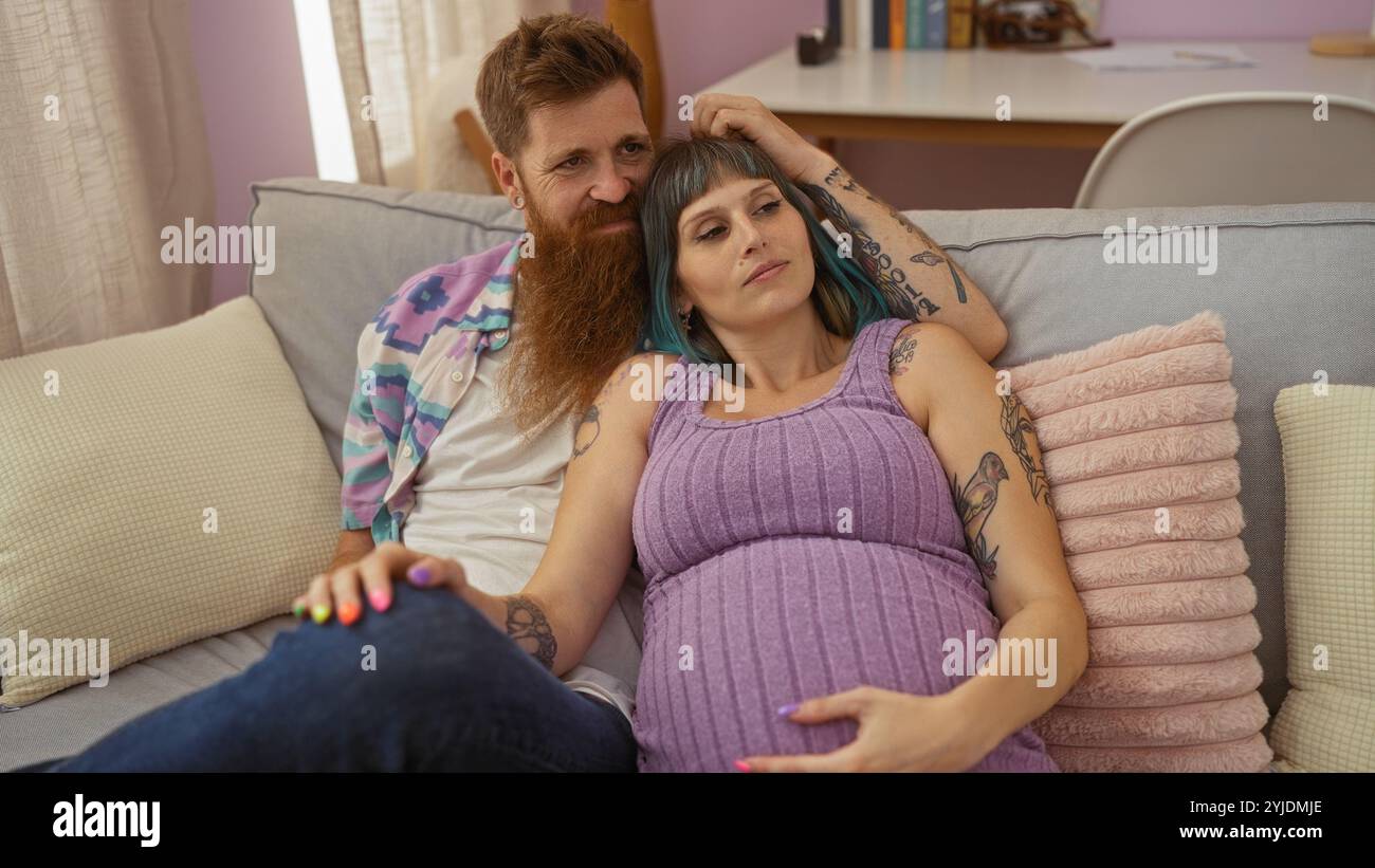 Pregnant woman and bearded man embracing on a couch in a cozy living ...