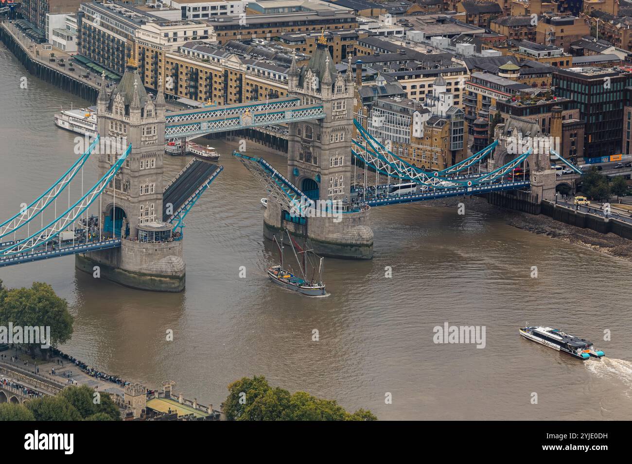 A tall mast boat passes under the raised Tower Bridge,completed in 1894 it is one of London 's most recognisable landmarks ,City Of London,UK Stock Photo
