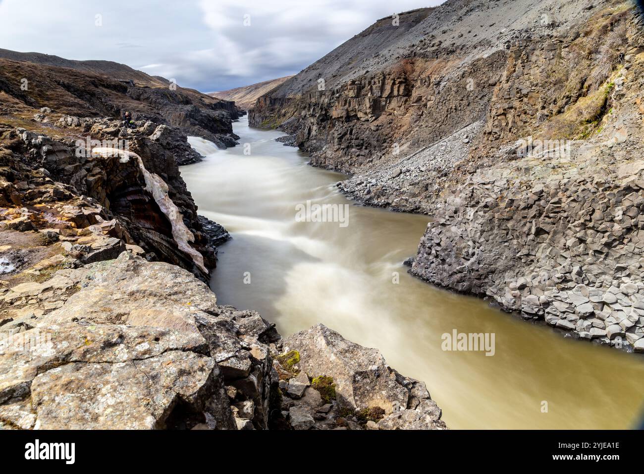 Studlagil Canyon (The Basalt Canyon) view of the ravine with brown glacial river and vertical hexagonal basalt columns, long exposure, Iceland. Stock Photo