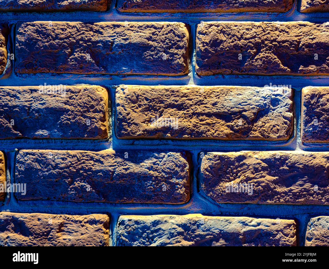 Illuminated  Red Brick Wall at Night: A Play of Light and Shadow. Stock Photo