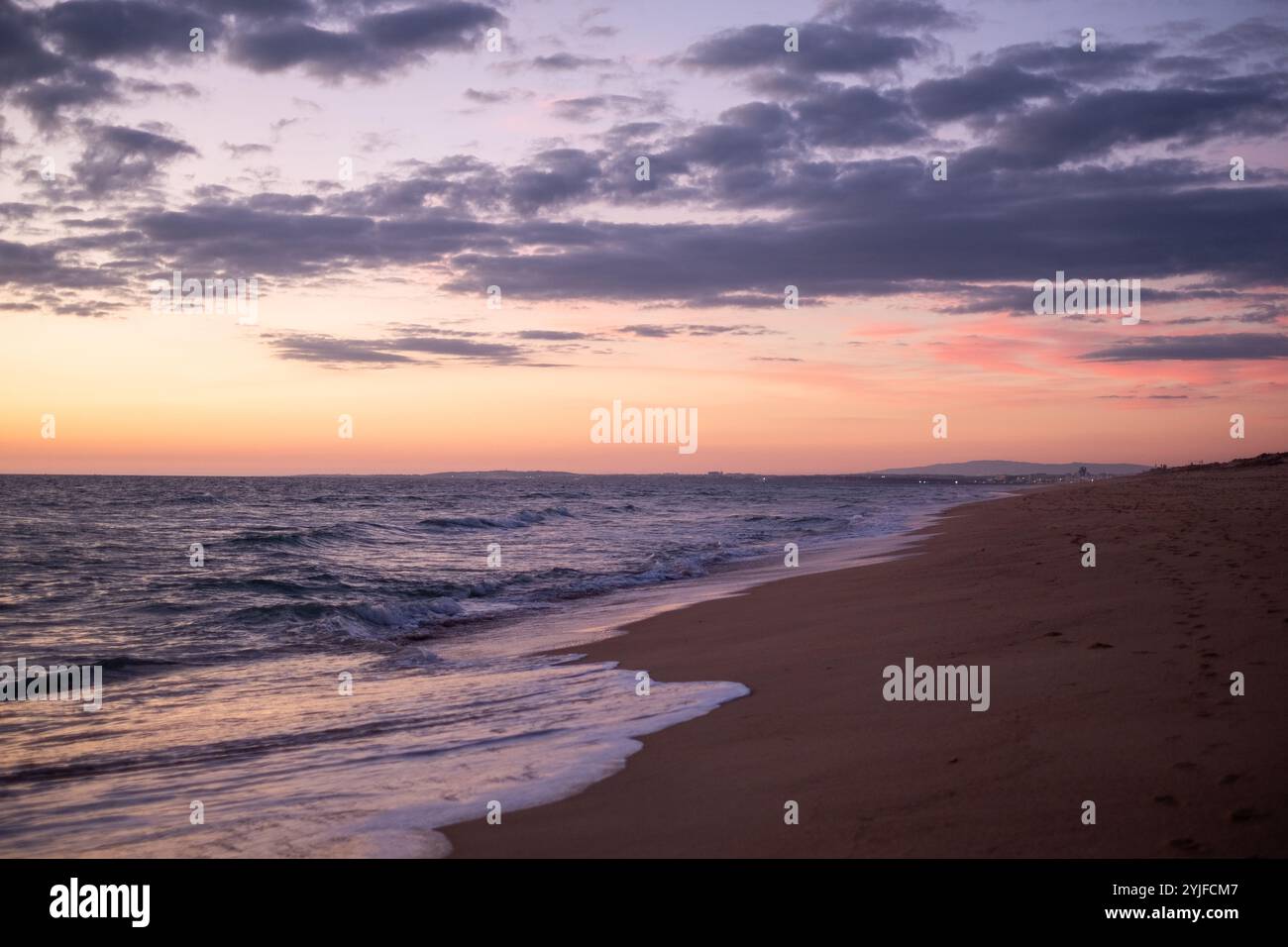 The sun sets over the horizon, casting a warm glow on the water as ...