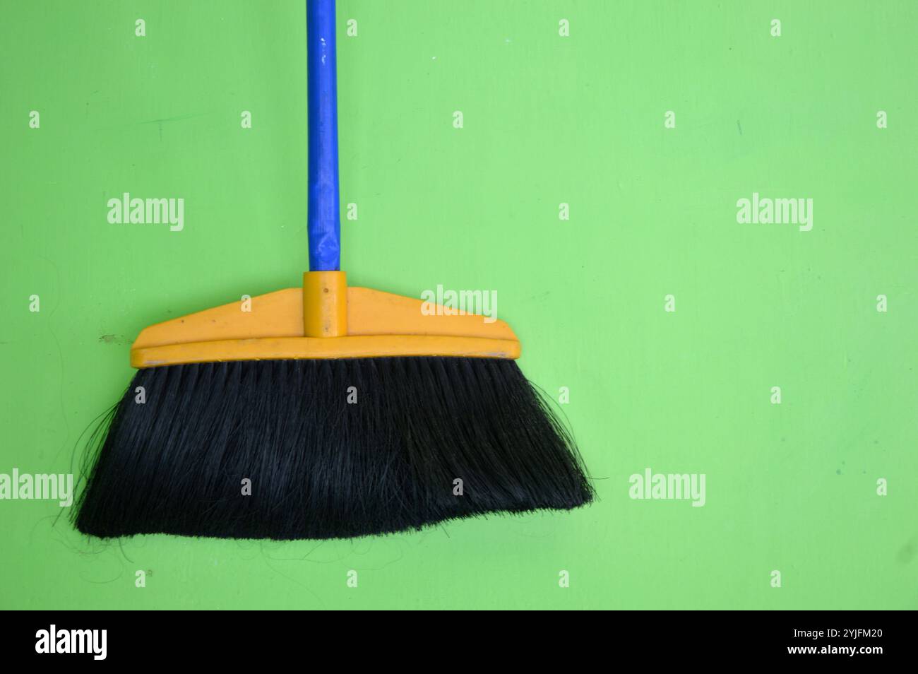 blue broom fibers on green wall Stock Photo