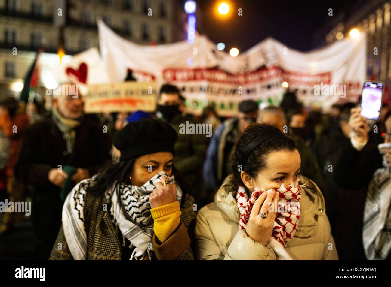 Two women cover her faces with their Keffiyeh scarfs, after the police fired tear gas, during the pro-palestinian demonstration against the organization of the pro-Israel gala 'Israel is Forever' in Paris. Thousands of people demonstrated in Paris against the gala organised by the far right in support of Israel, ‘Israel Is Forever'. The rally, under heavy police surveillance, was organised by left-wing parties and trade unions, left-wing Jewish movements and pro-Palestinian groups. Bezalel Smotrich, the Israeli Finance Minister, known for his extreme positions on Gaza, who was due to take part Stock Photo