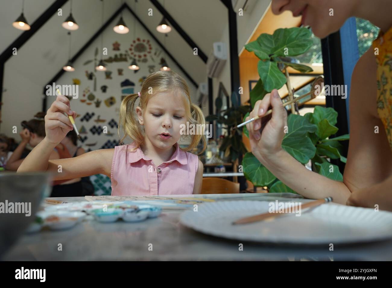 A young mother and her daughter enjoy a creative art session at home ...