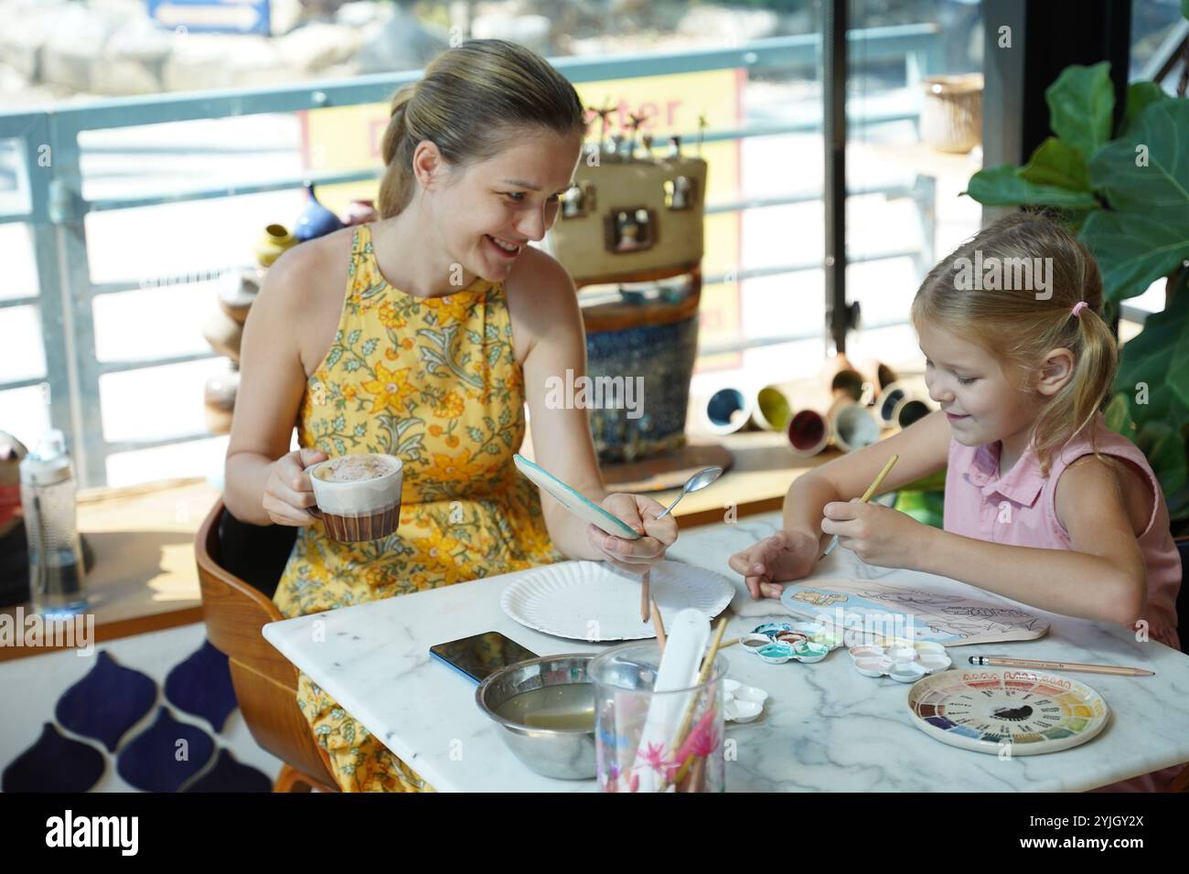 A young mother and her daughter enjoy a creative art session at home ...