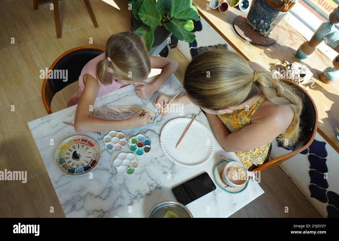 A young mother and her daughter enjoy a creative art session at home ...