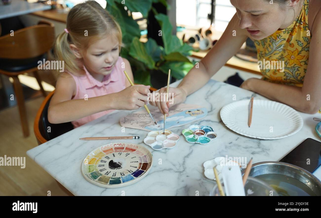 A young mother and her daughter enjoy a creative art session at home ...