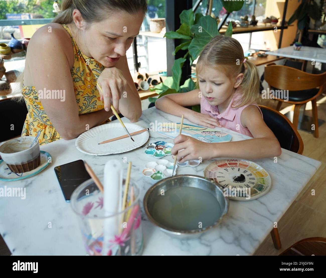 A young mother and her daughter enjoy a creative art session at home ...