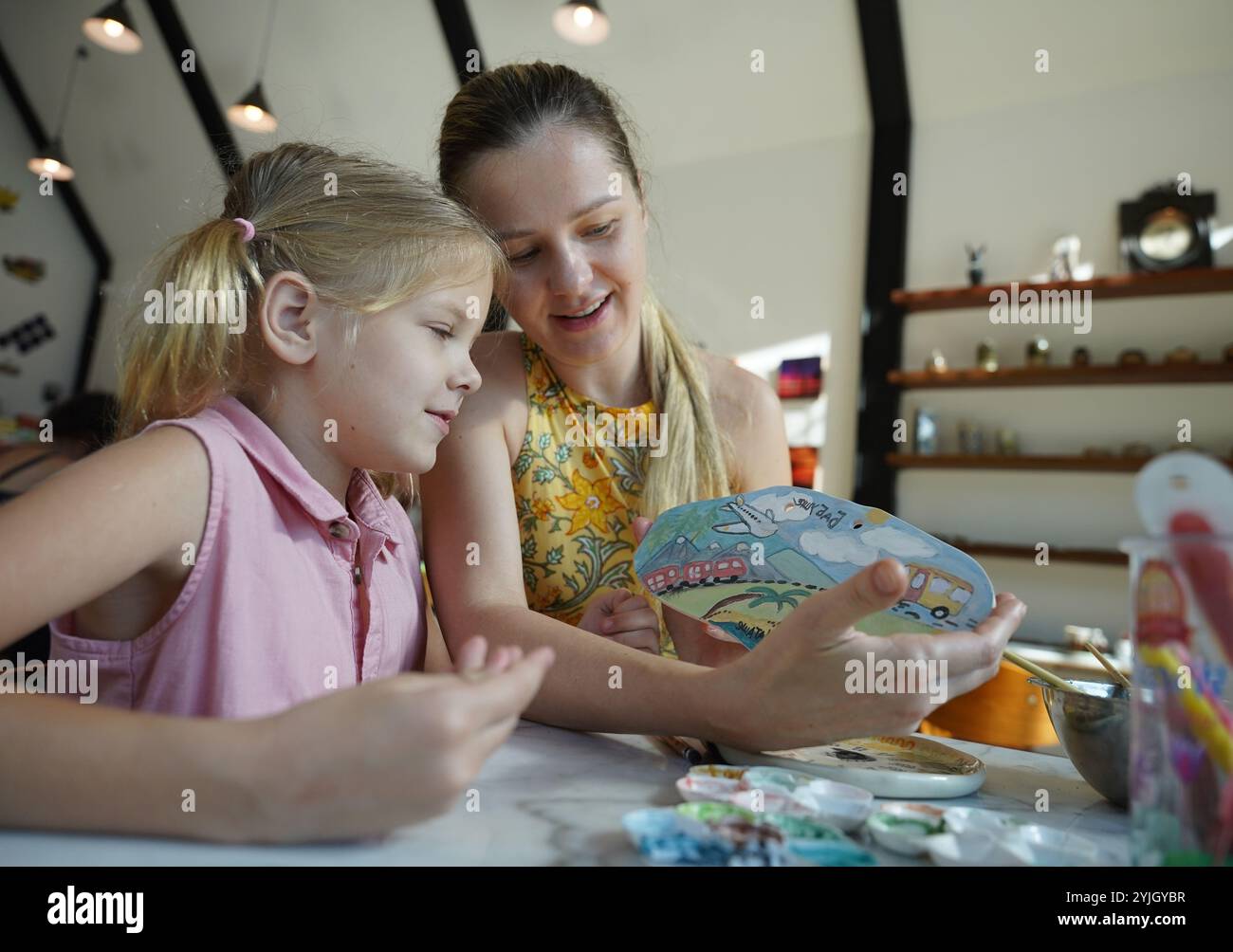 A young mother and her daughter enjoy a creative art session at home ...
