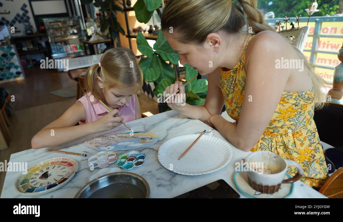 A young mother and her daughter enjoy a creative art session at home ...
