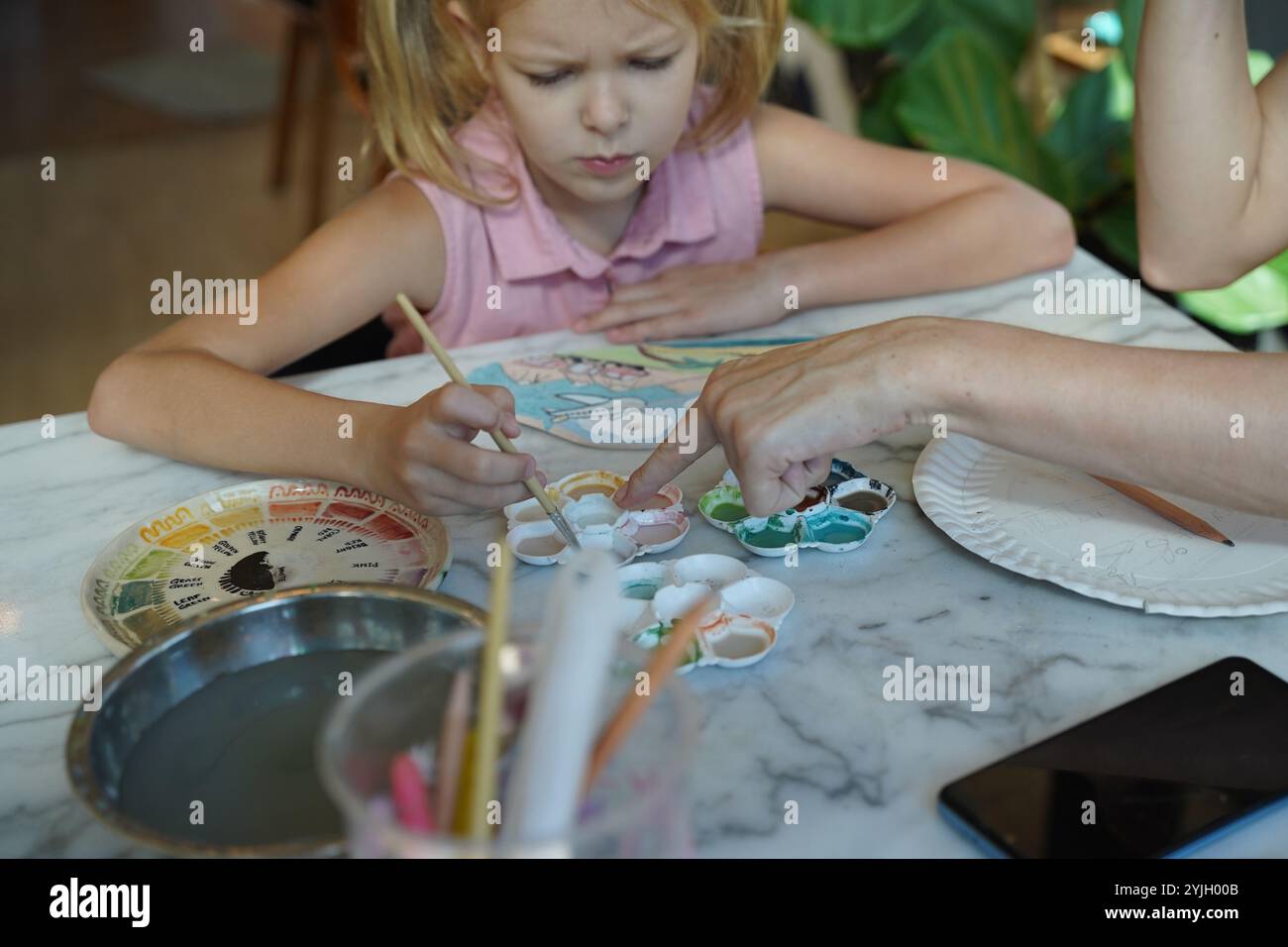 A young mother and her daughter enjoy a creative art session at home ...
