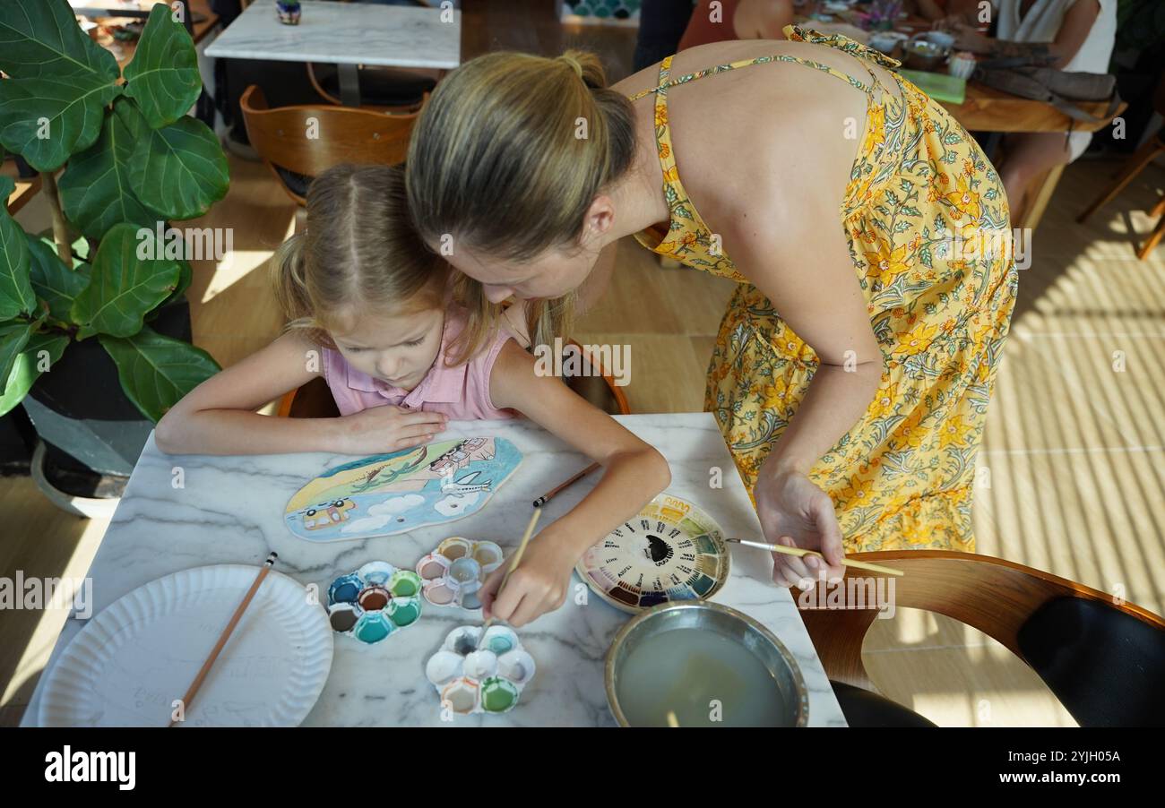 A young mother and her daughter enjoy a creative art session at home ...
