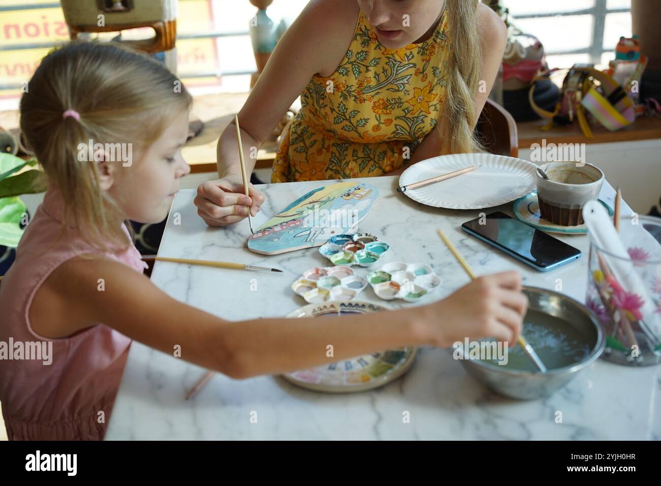 A young mother and her daughter enjoy a creative art session at home ...