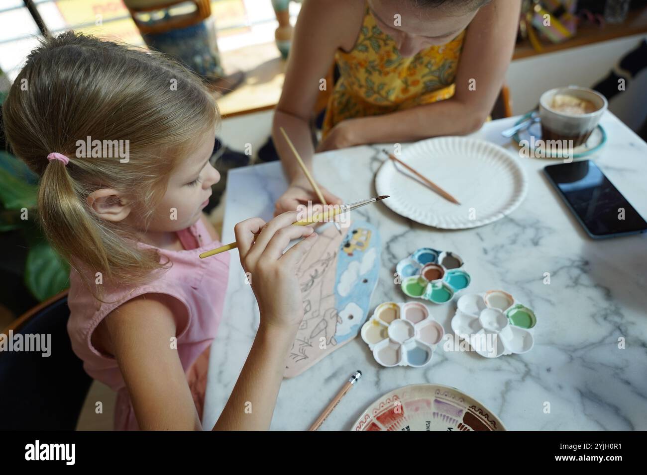 A young mother and her daughter enjoy a creative art session at home ...