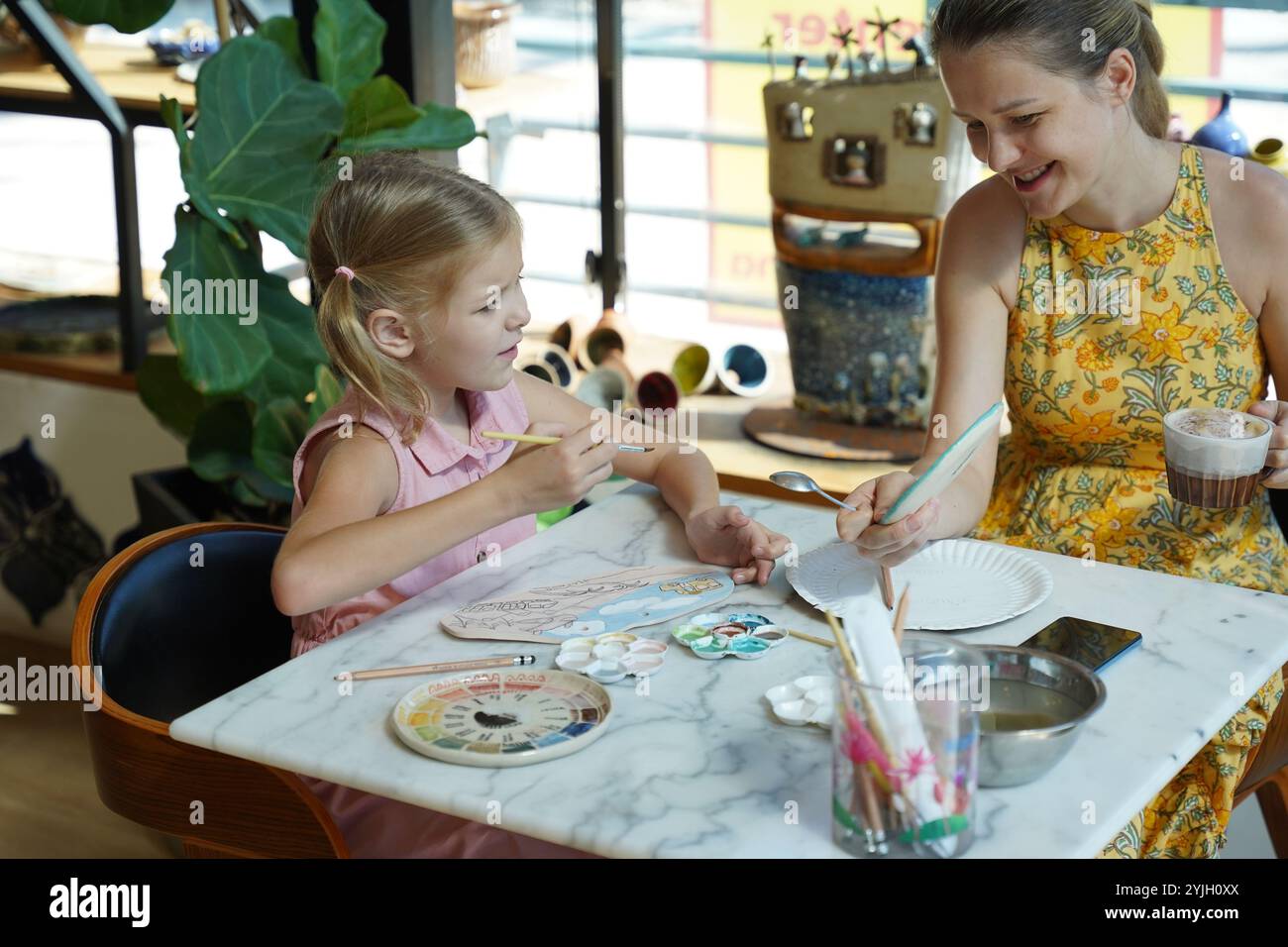 A young mother and her daughter enjoy a creative art session at home ...