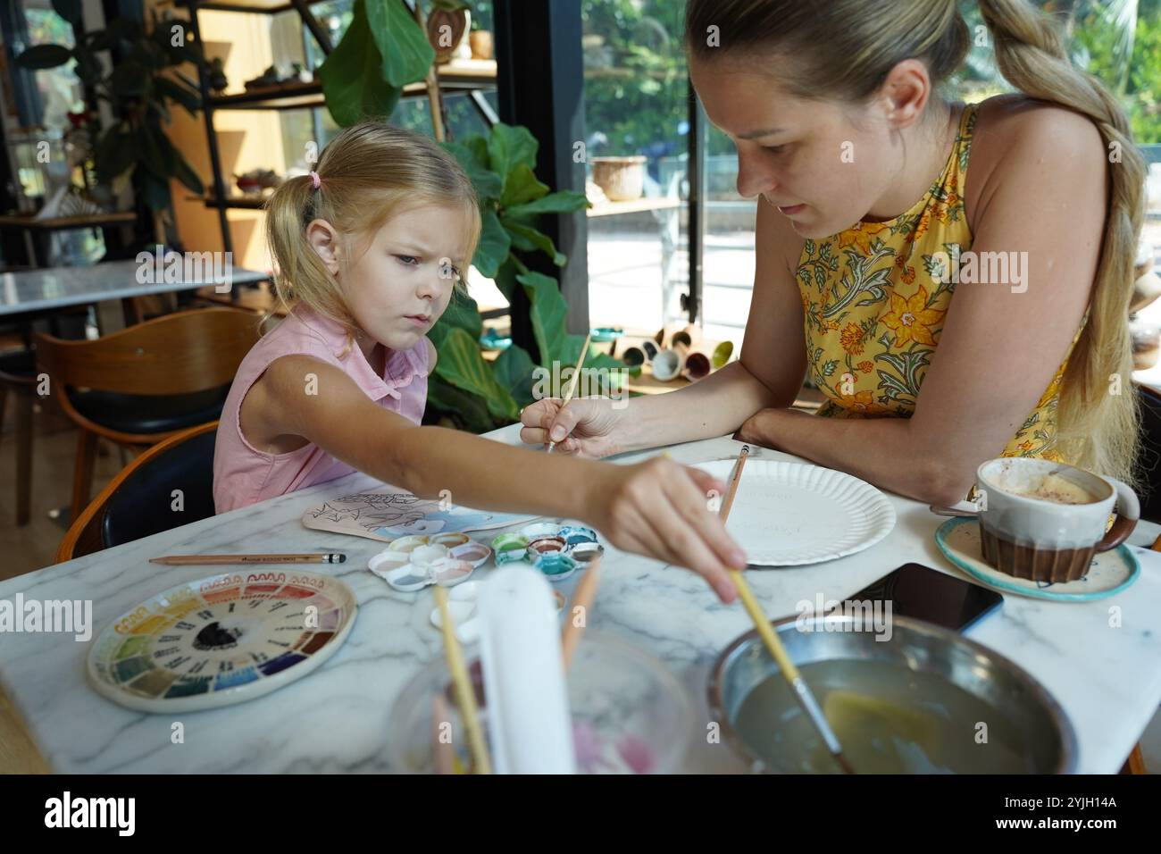 A young mother and her daughter enjoy a creative art session at home ...