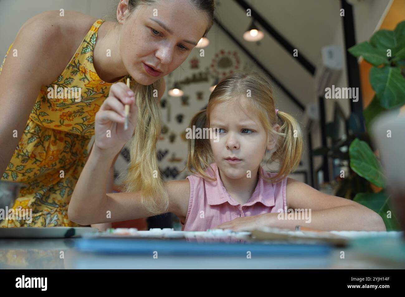 A young mother and her daughter enjoy a creative art session at home ...
