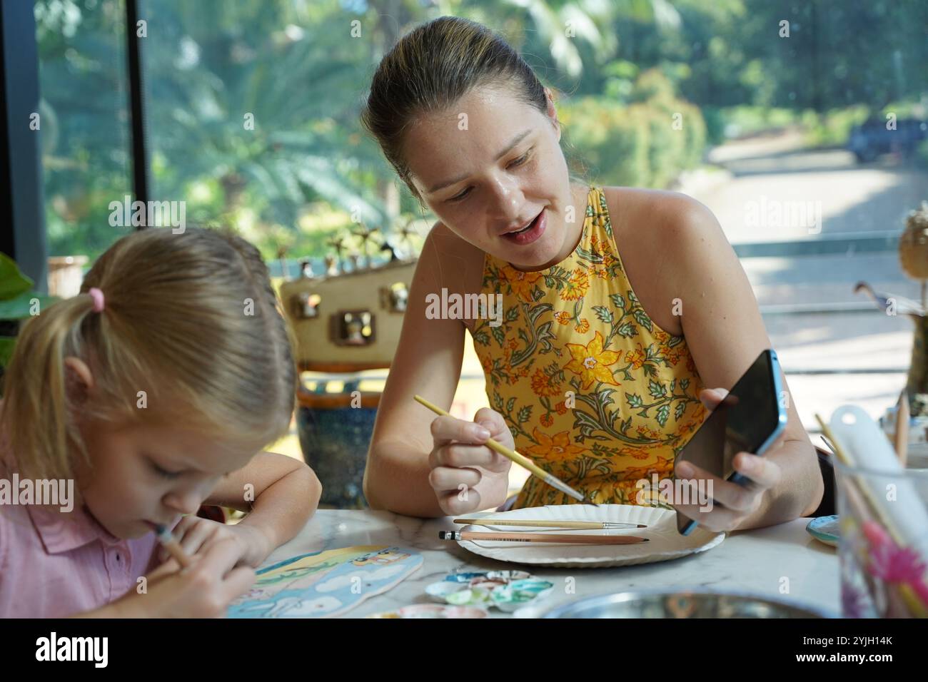 A young mother and her daughter enjoy a creative art session at home ...