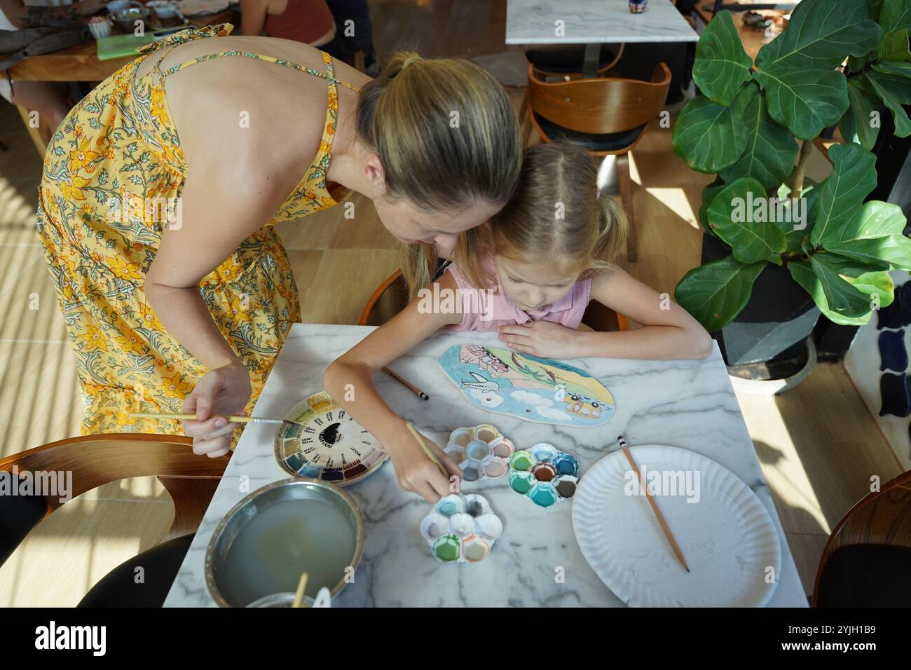 A young mother and her daughter enjoy a creative art session at home ...