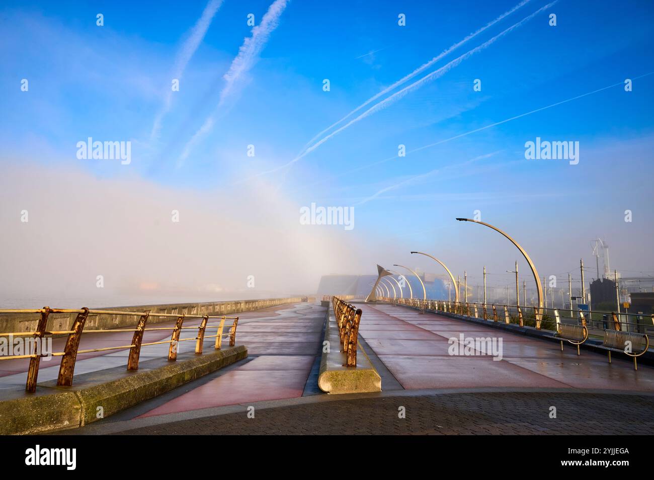 Fog bank moves away to reveal contrails in a blue winter sky above Blackpool Stock Photo