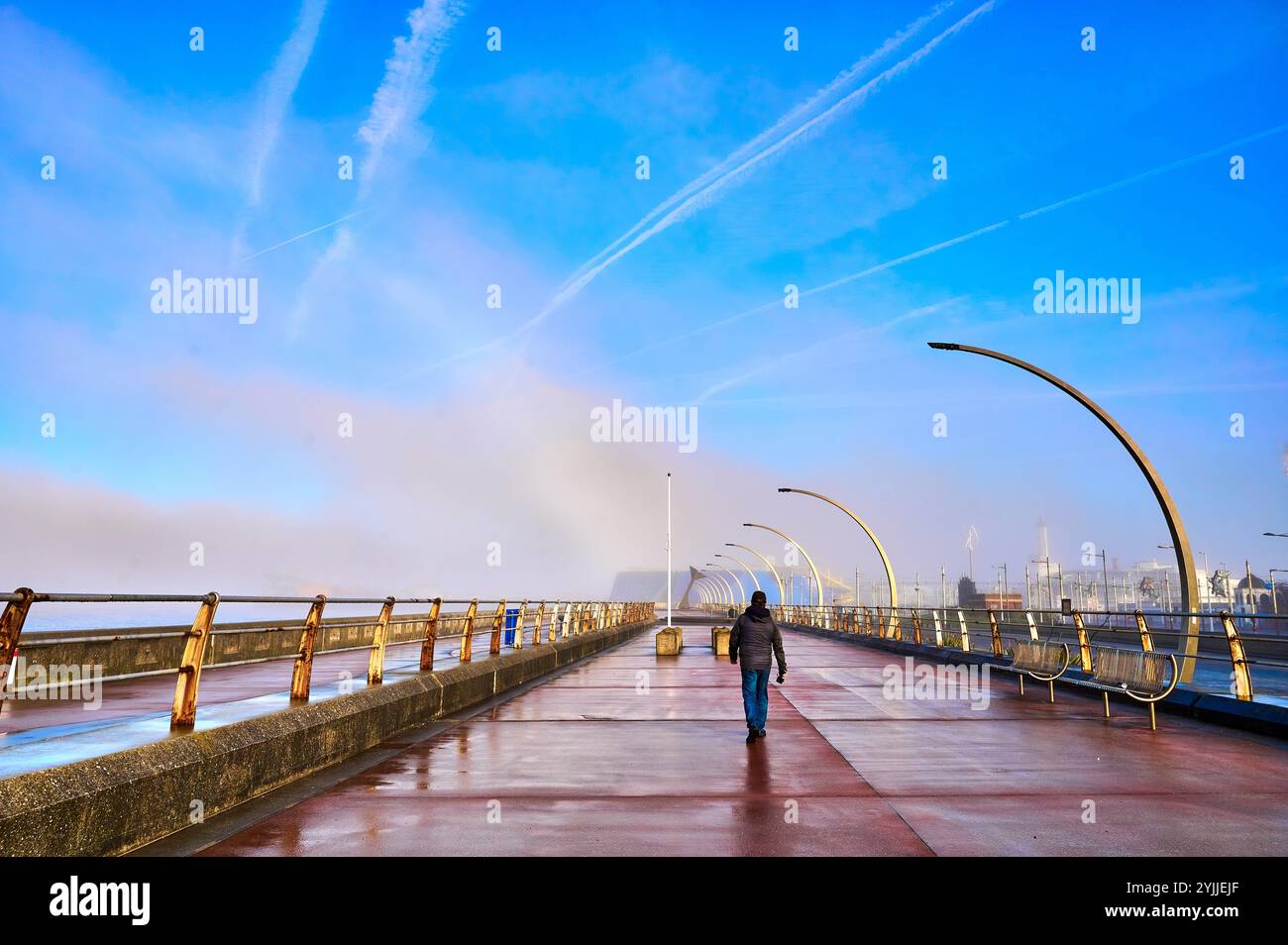 Fog bank moves away to reveal contrails in a blue winter sky above Blackpool Stock Photo