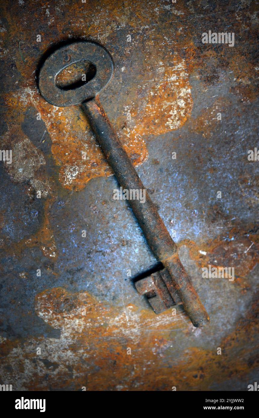 rusting old door key on rusting metal surface Stock Photo