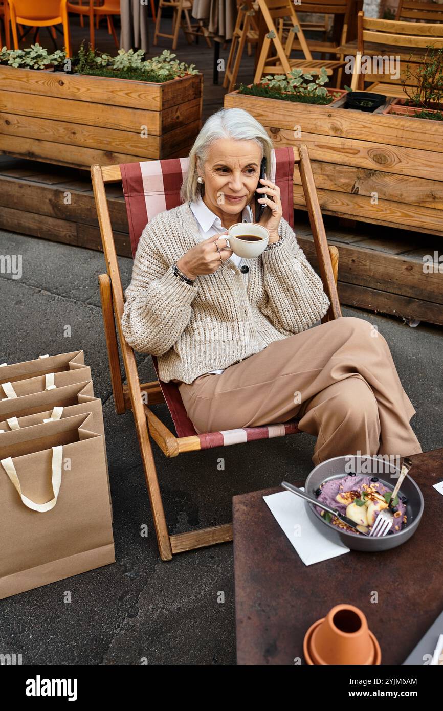 A beautiful mature woman with gray hair relaxes, drinking coffee and ...