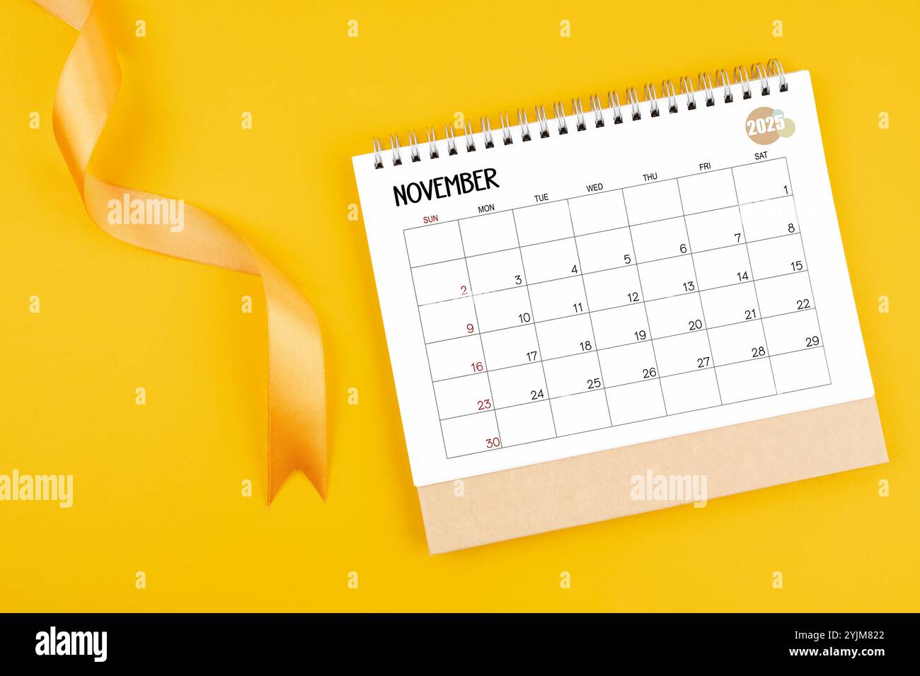 November 2025 desk calendar with yellow ribbon on yellow background ...