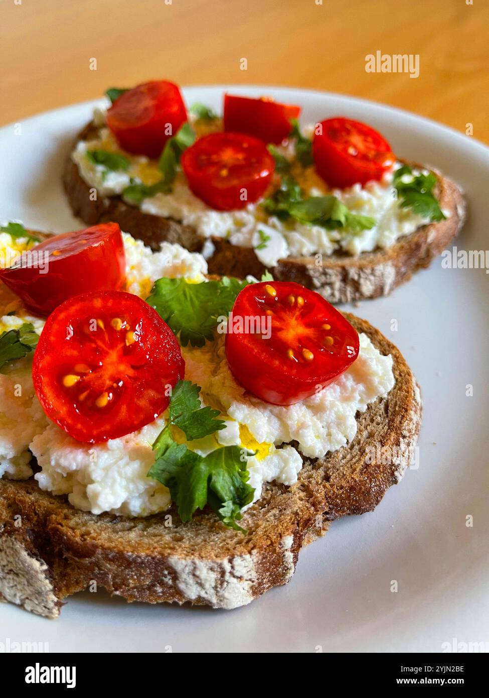 Cottage cheese with cherry tomatoes, coriander and olive oil on toast. - Smartphone Captured Stock Image
