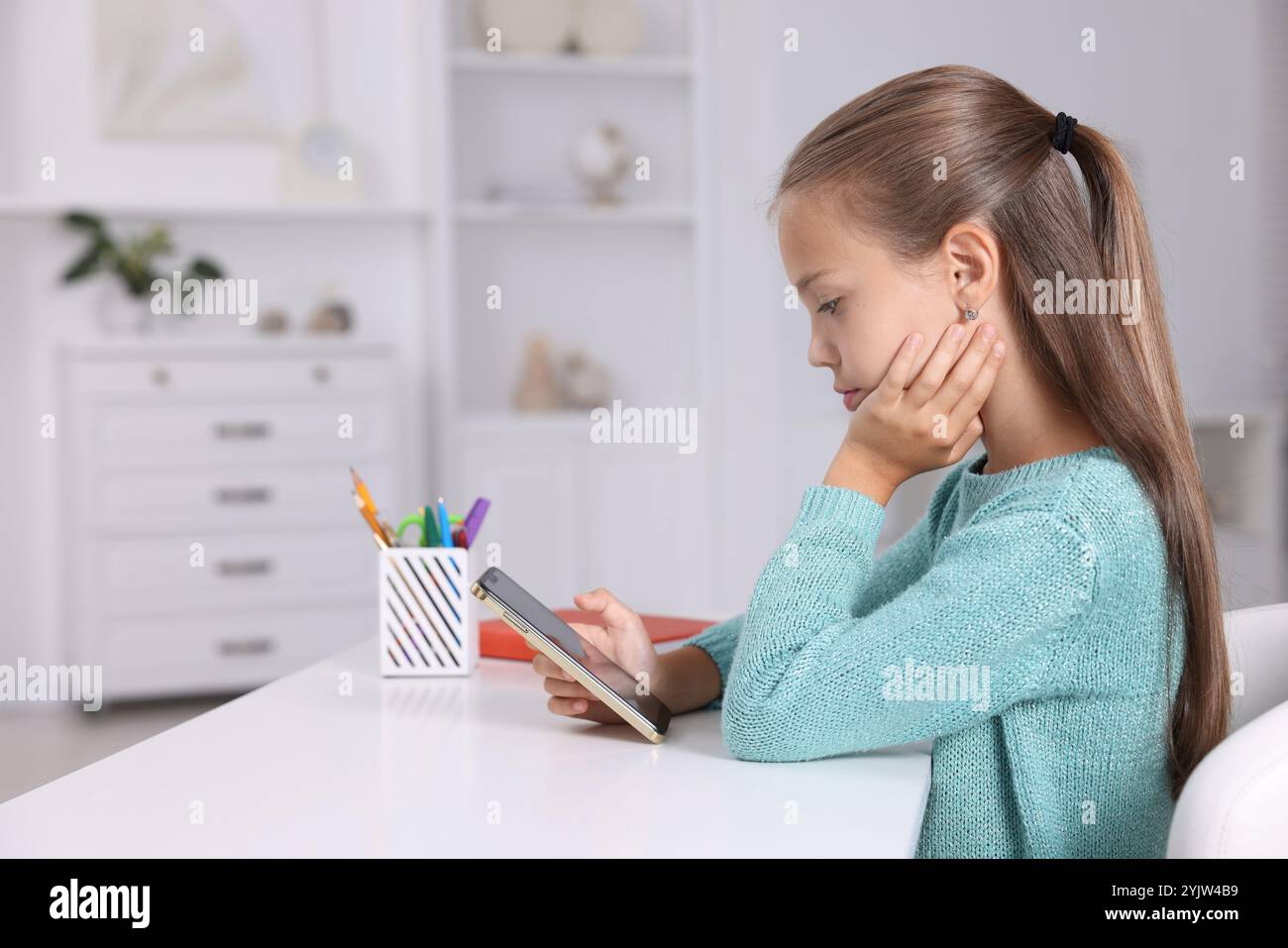 Girl with correct posture using smartphone at white desk indoors Stock ...