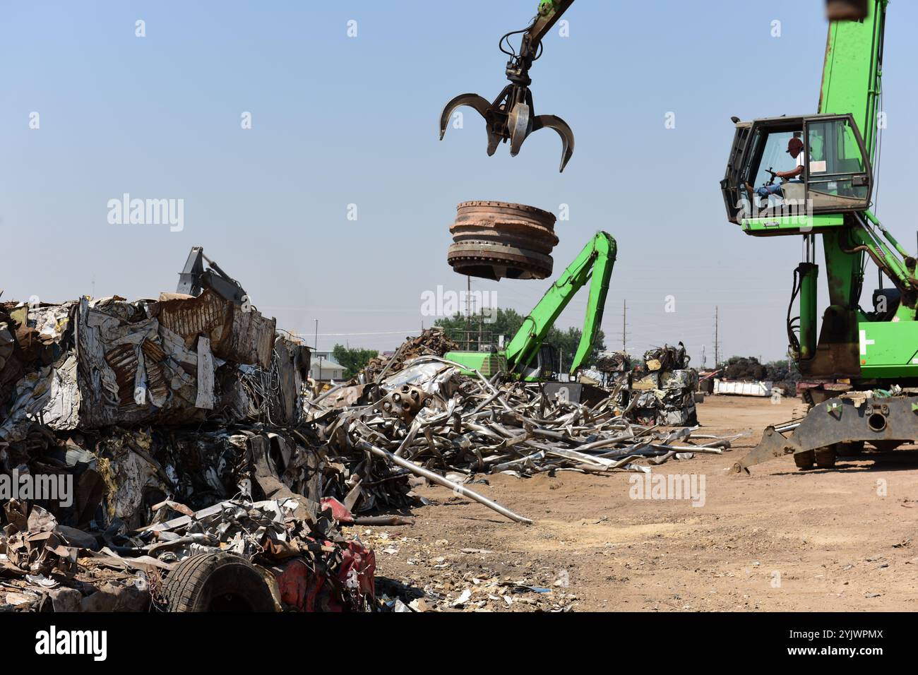 Industrial cranes processing discarded scrap iron metals, recycling center in the United States. Stock Photo