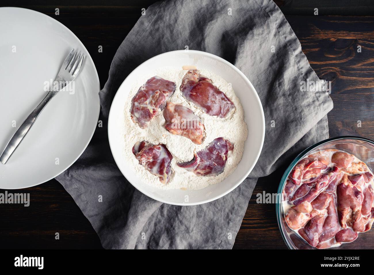 Breading Chicken Livers Soaked in Milk: Dredging raw chicken livers in a bowl of spiced and seasoned flour Stock Photo
