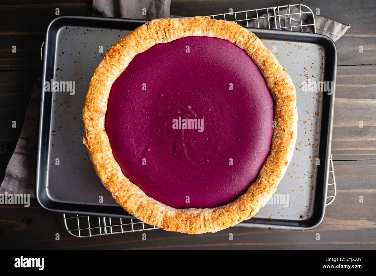 Purple Sweet Potato Pie with Pecan Shortbread Cookie Crust: Directly above a homemade sweet potato pie on a sheet pan and wire cooling rack Stock Photo