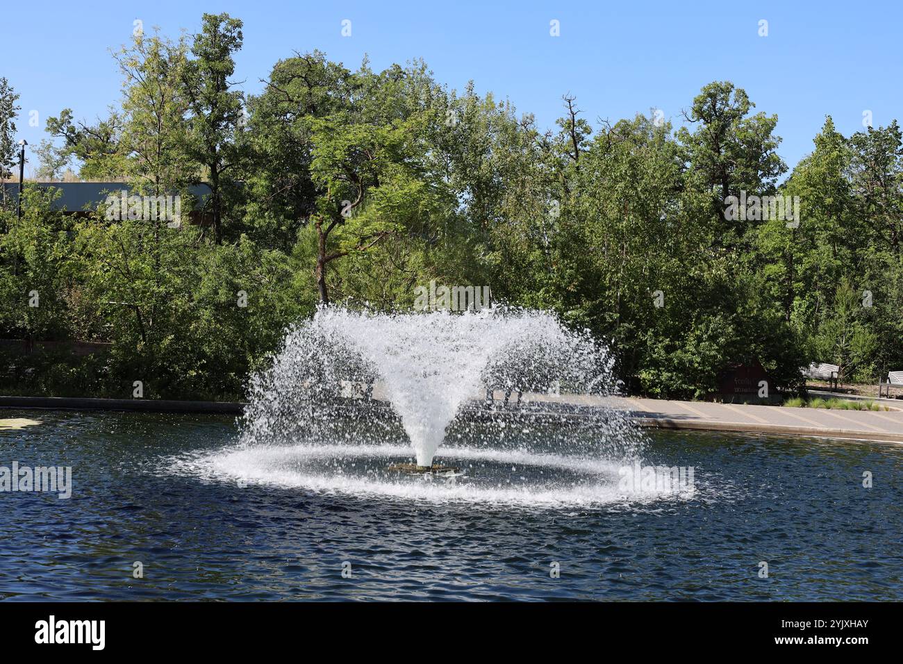 fountain in a pond under cloudless blue sky Stock Photo