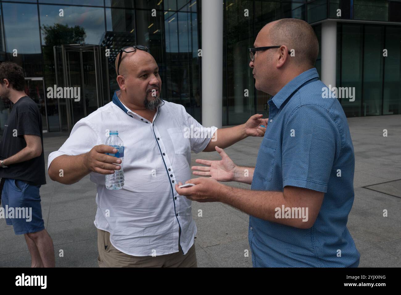 London, UK. 7th July 2017.  Alberto Durango of CAIWU (left) who led the protest talks with Commercial  Director of Peartree Cleaning Services Stuart Conroy who had come to watch it. The Cleaners and Allied Independent Workers Union (CAIWU) protested outside Facebook's offices in London against the 'Ugly Face of Facebook' calling for the cleaners there to be paid the London Living Wage and for a proper investigation into allegations of racism, bullying and nepotism by the manager on site. There are two redundant levels of management at these offices; rather than employing cleaners directly, Fac Stock Photo