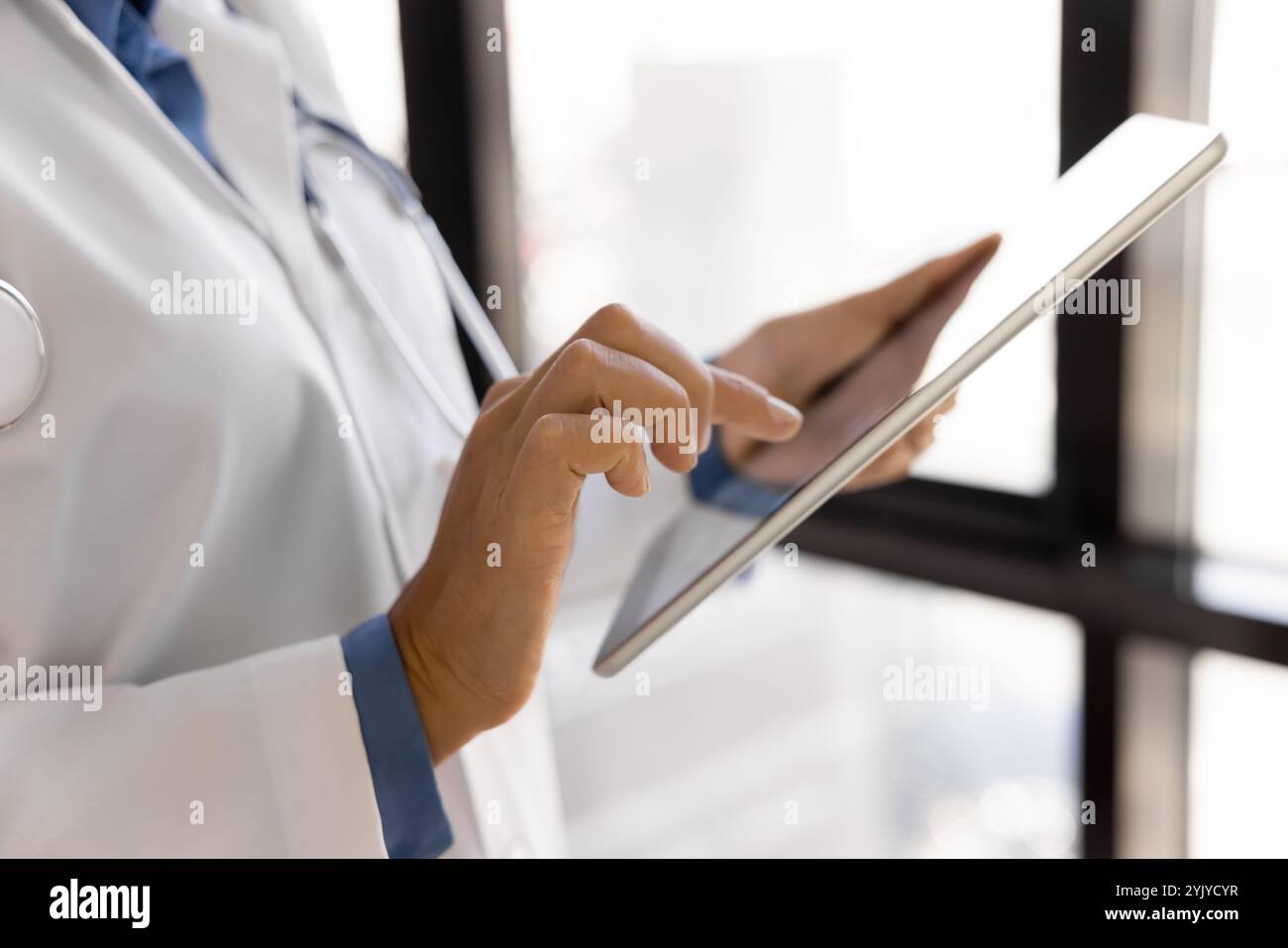 Closeup female therapist in white lab coat using modern tablet Stock Photo