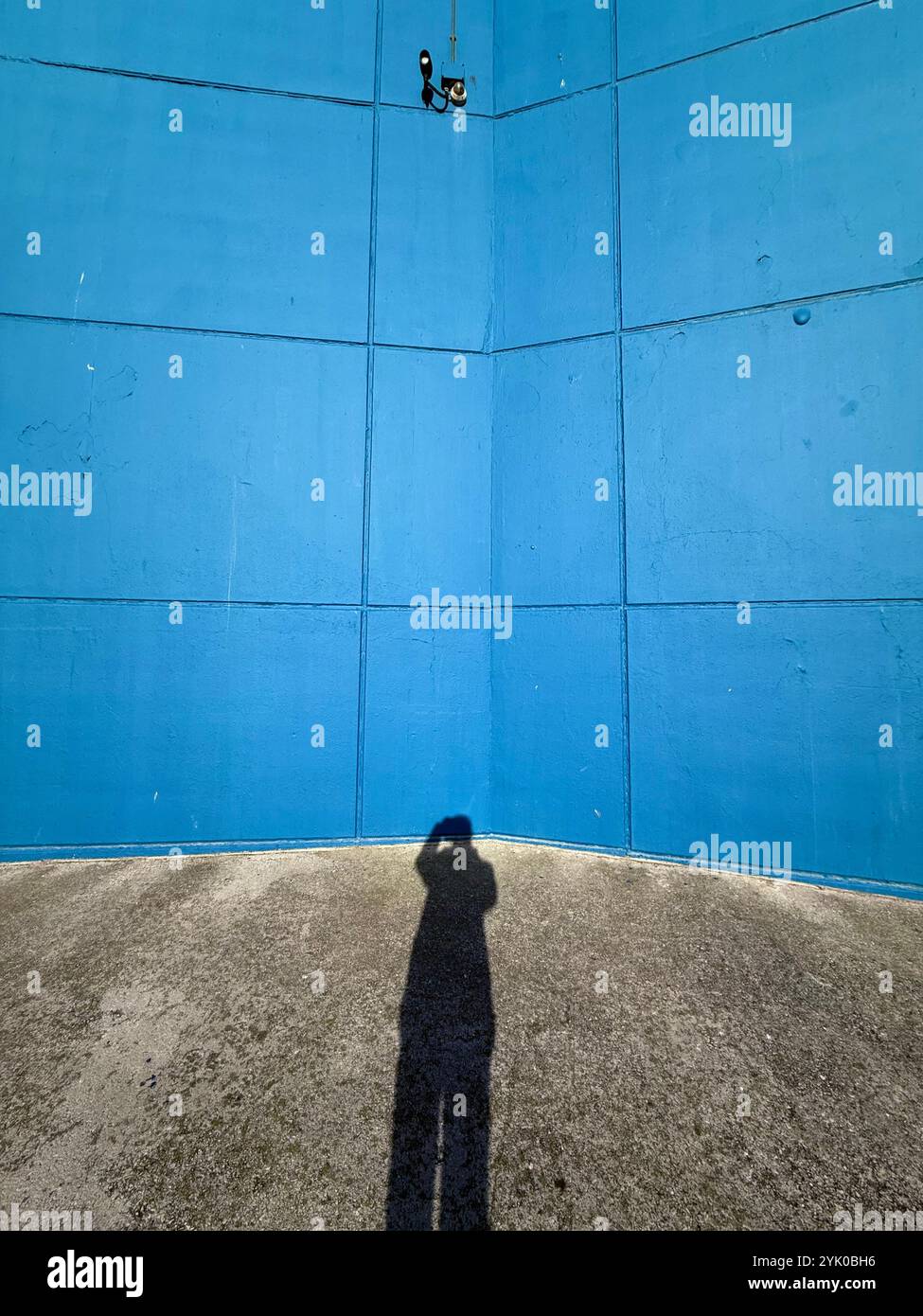 CCTV camera and shadow of figure on blue wall of Sandcastle Swimming Complex, Blackpool, UK - Smartphone Captured Stock Image