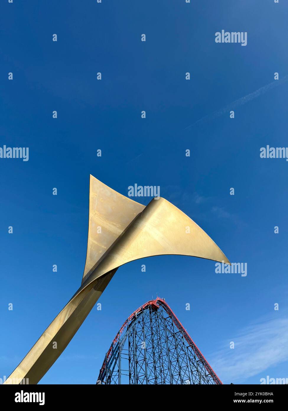 Abstract fin (Whale's Tail) on bench on Blackpool South promenade with the Big One rollercoaster ride in background against a blue sky. Blackpool, UK - Smartphone Captured Stock Image