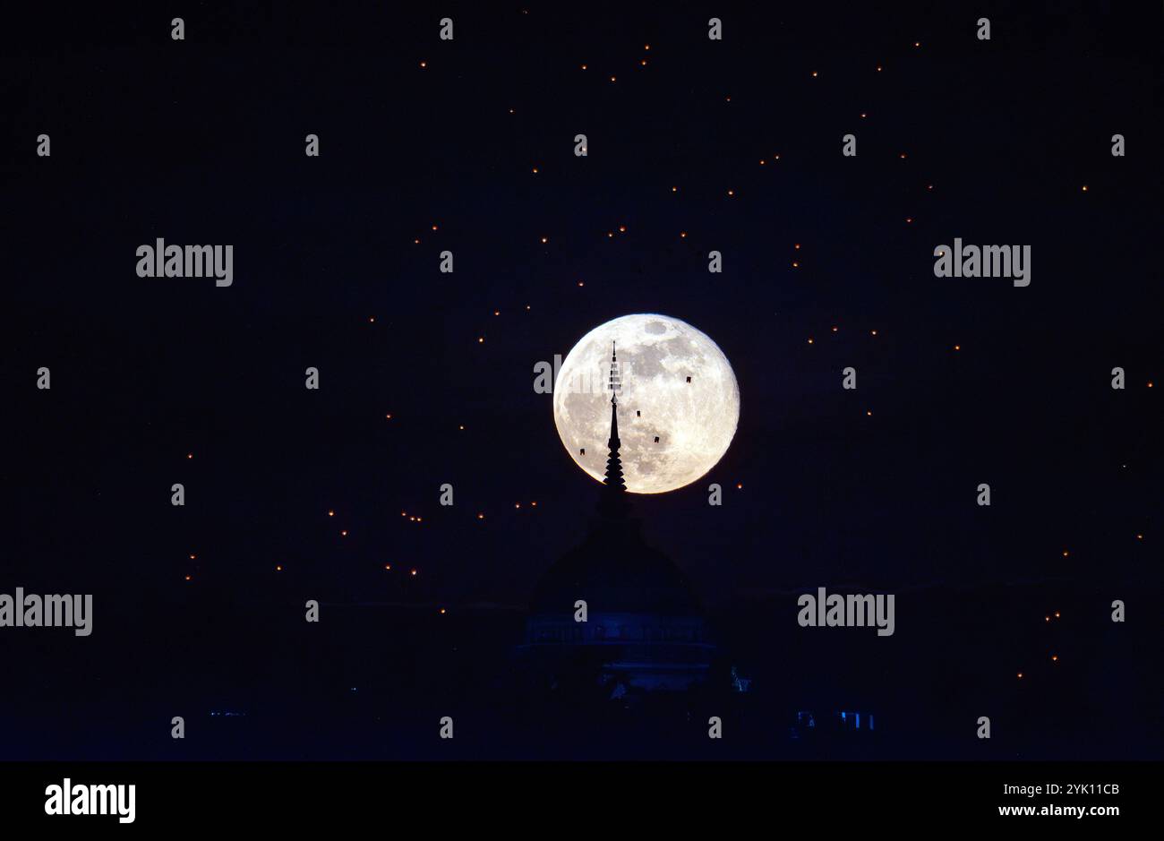 The full moon rises behind the Buddha’s Footprint of Yonok City, accompanied by Lanna-style floating lanterns on Loy Krathong Day at Wat Phra That Doi Saket. Stock Photo