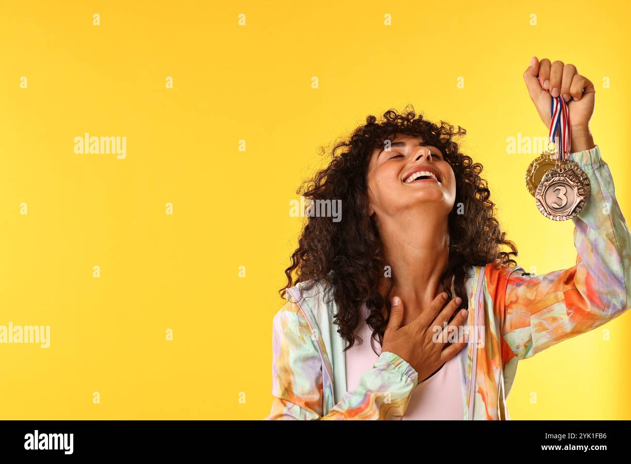Happy winner showing different medals on yellow background. Space for ...