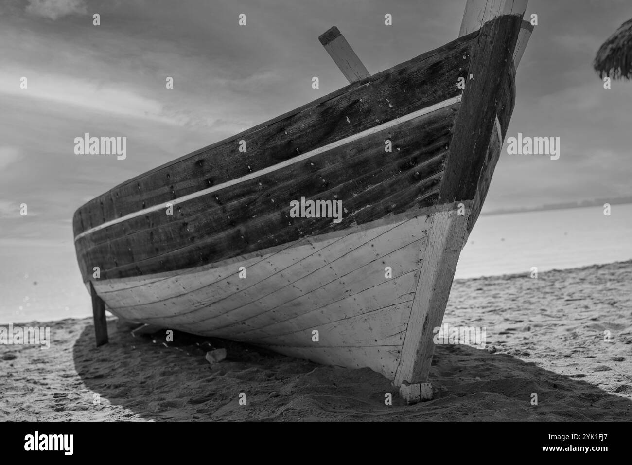 Old wooden fishing boat on the beach and sky up the horison in black ...