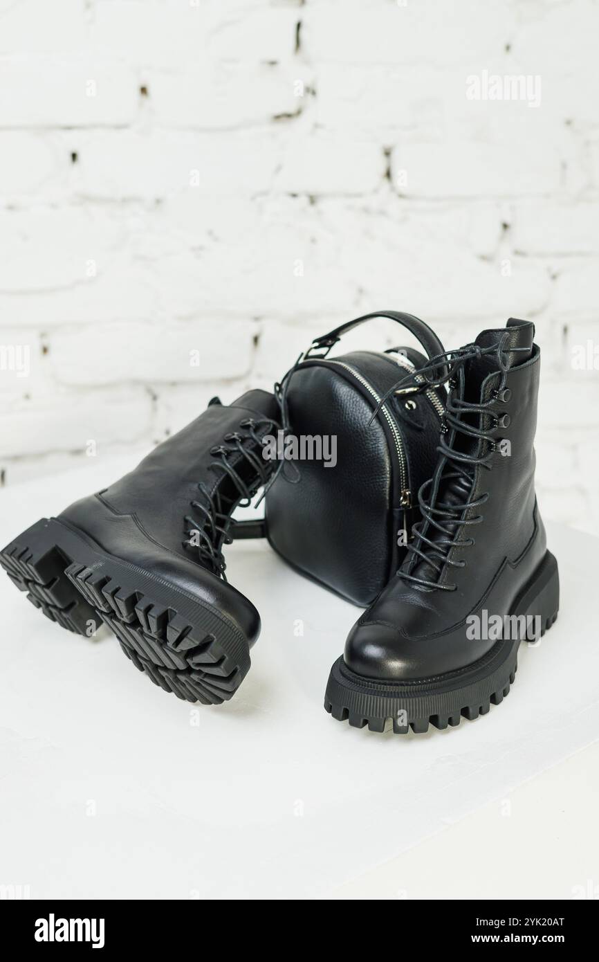 Women's black leather boots and a black leather backpack stand on a white background. Women's fashion Stock Photo