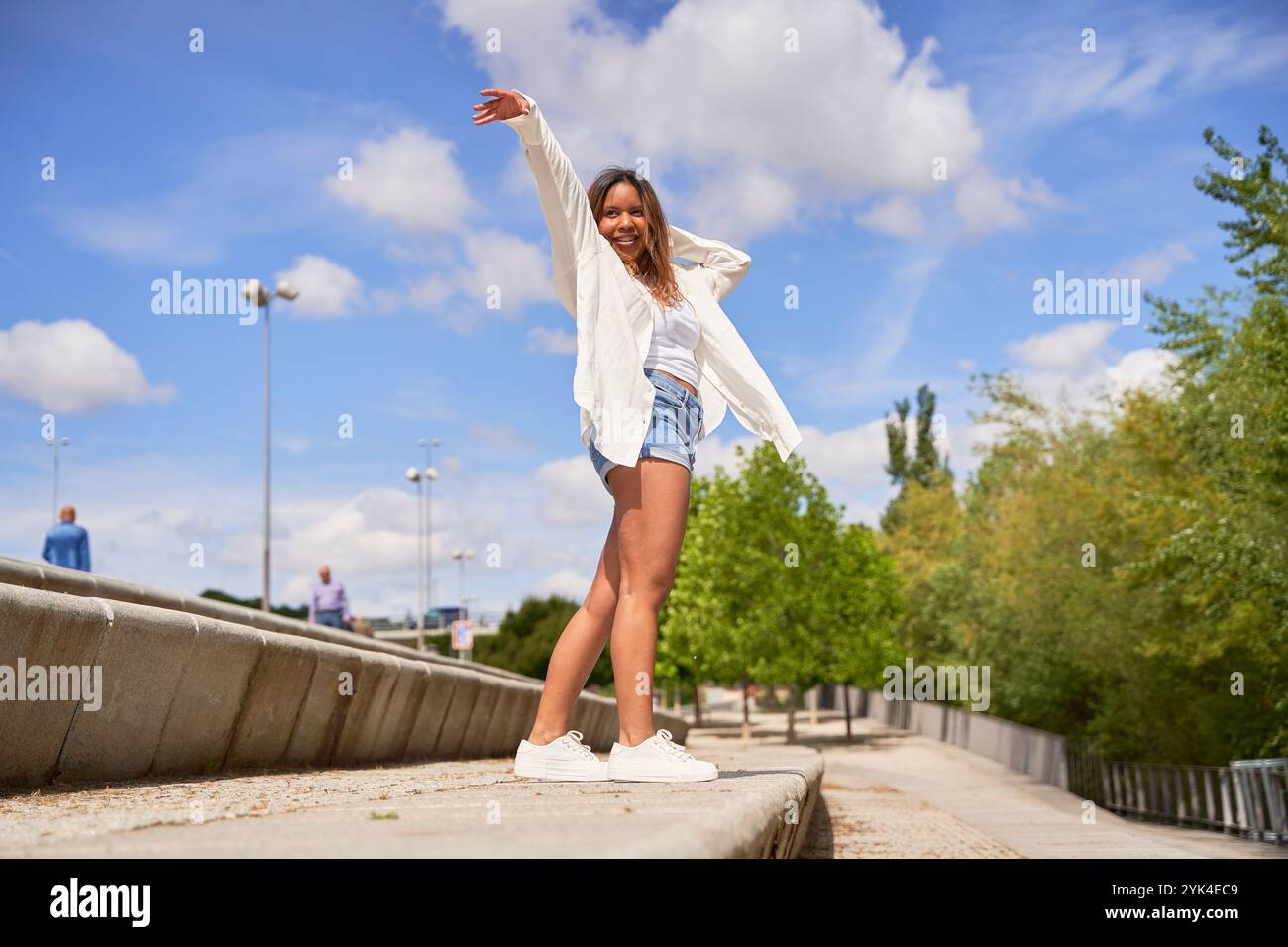 A Latina woman performs various dance poses in a park, showcasing her grace and passion for dance amidst a natural, outdoor setting. Stock Photo