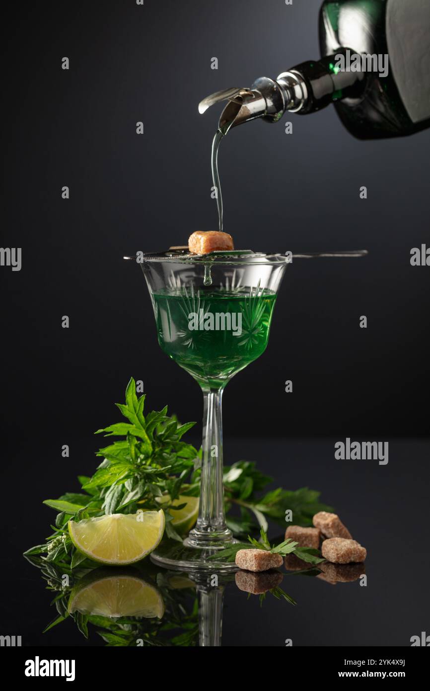Absinthe is poured from an vintage bottle into a glass. Preparation of ...