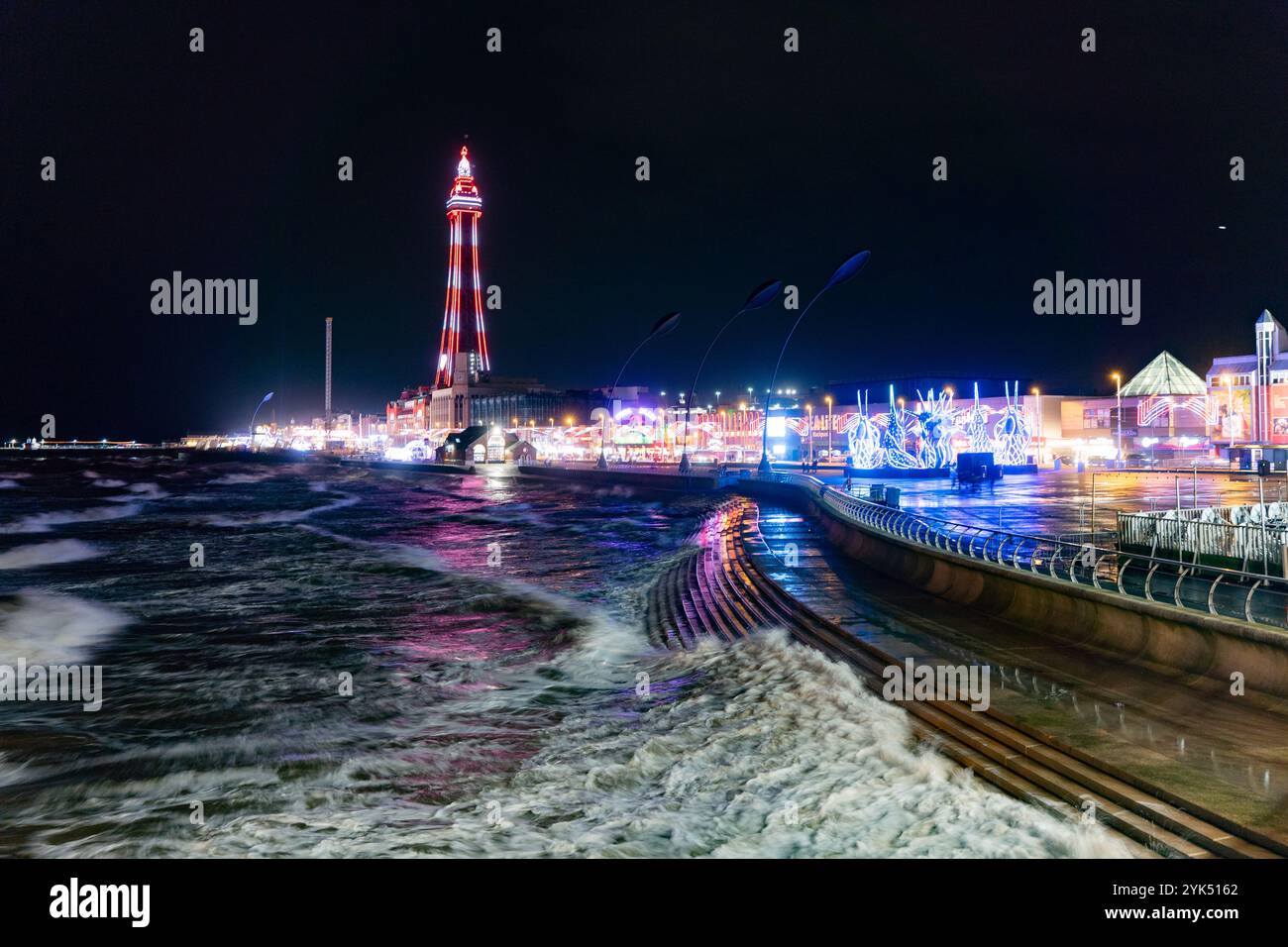 Blackpool Tower, lit up for the 2024 illuminations, casts a colourful glow across the waters of the Irish Sea Stock Photo