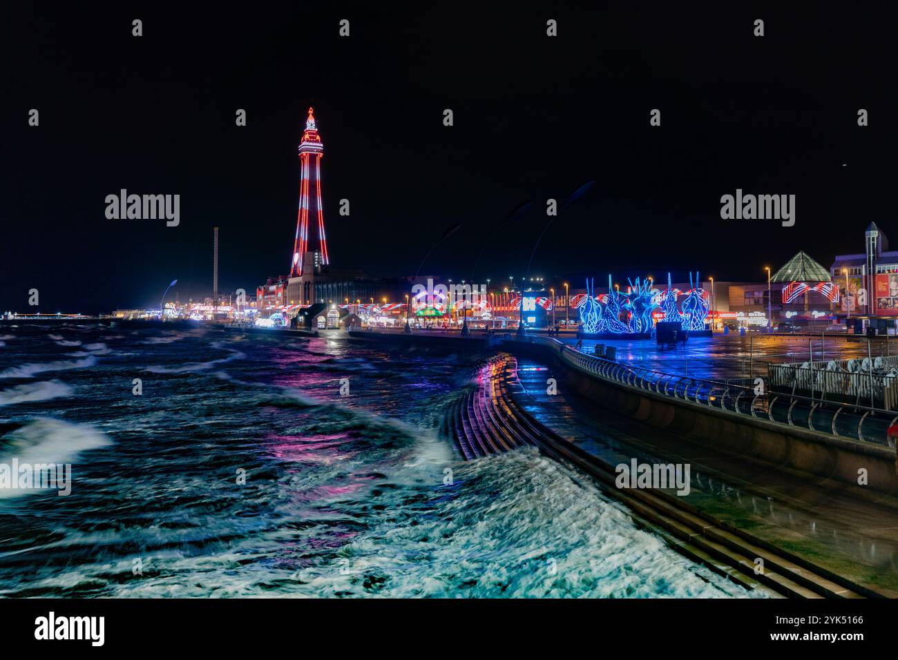 Blackpool Tower, lit up for the 2024 illuminations, casts a colourful glow across the waters of the Irish Sea Stock Photo