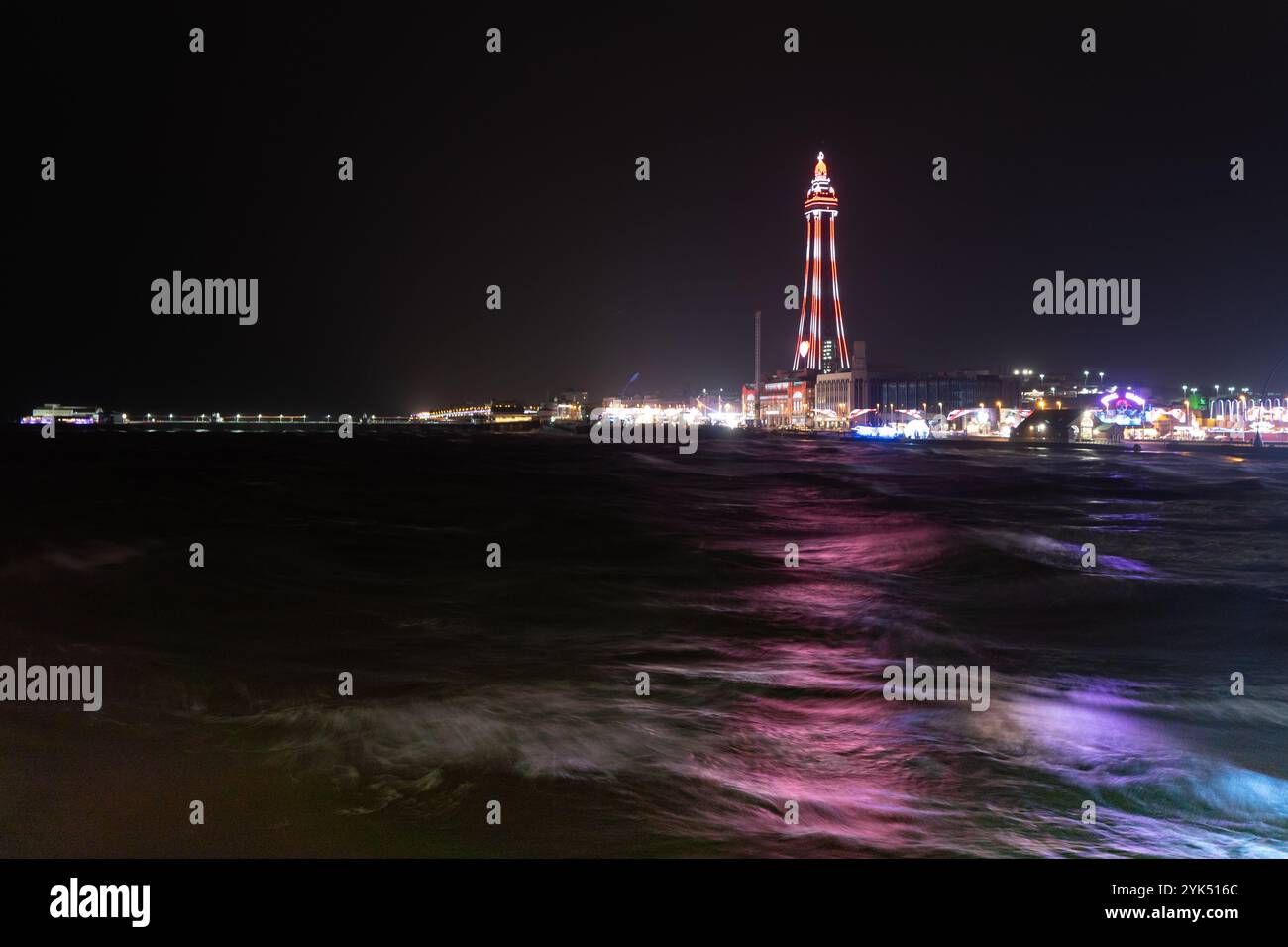 Blackpool Tower, lit up for the 2024 illuminations, casts a colourful glow across the waters of the Irish Sea Stock Photo