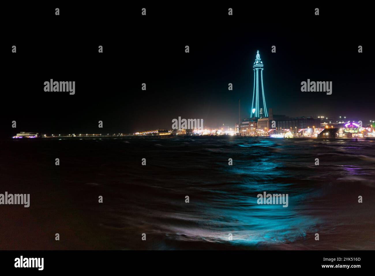 Blackpool Tower, lit up for the 2024 illuminations, casts a colourful glow across the waters of the Irish Sea Stock Photo