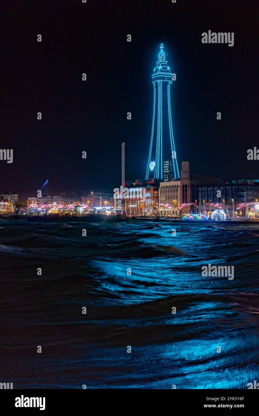 Blackpool Tower, lit up for the 2024 illuminations, casts a colourful glow across the waters of the Irish Sea Stock Photo